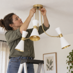 How to fit a ceiling light: a step-by-step guide A woman installing a ceiling light in her living room